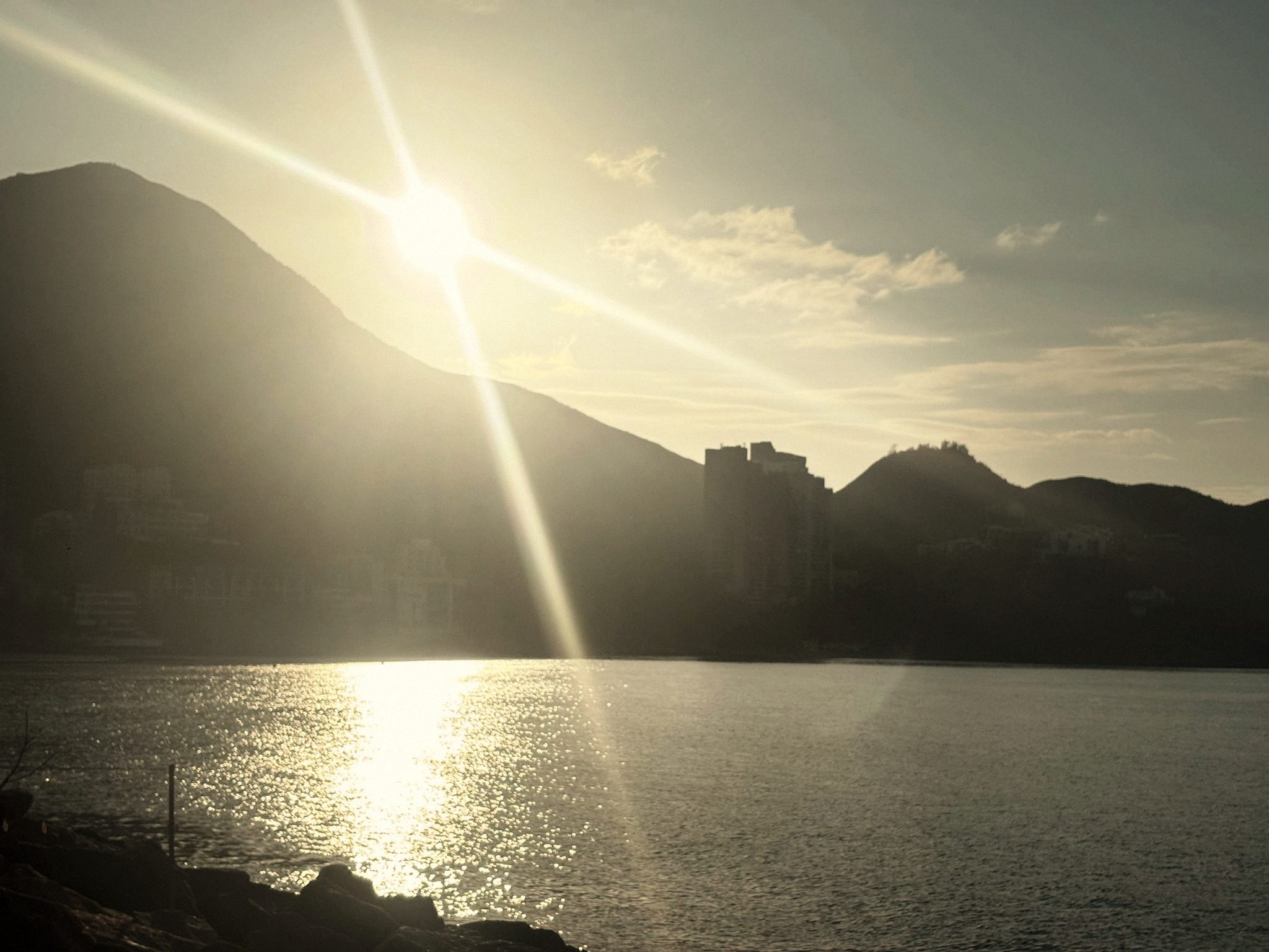 The sun cresting the ridge above Repulse Bay, Hong Kong, its light scattered across the water.